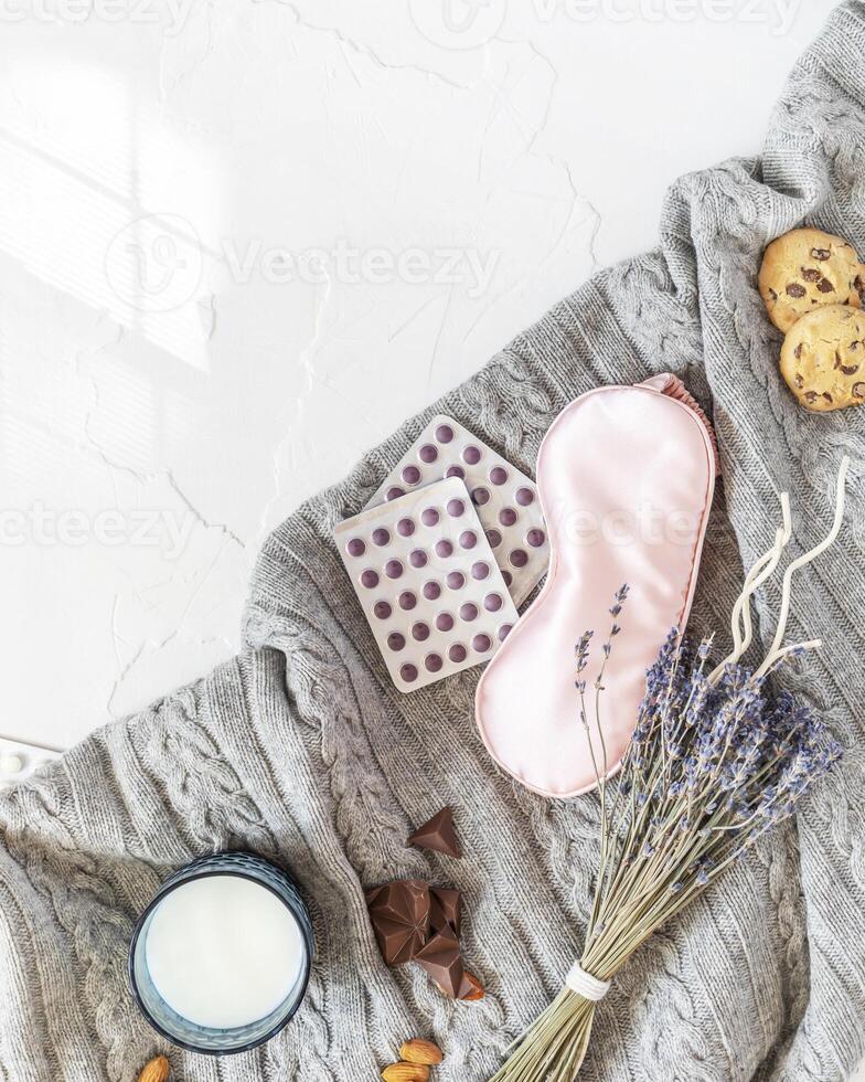 knitted blanket with a mask for sleep, pills, a bouquet of lavender, a glass of milk and sweet snack for good sleep photo
