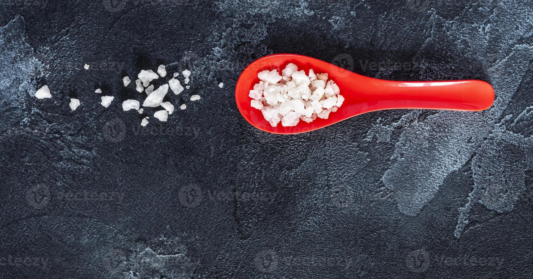 Oriental style flat lay with red spoon with sea salt on a black background photo