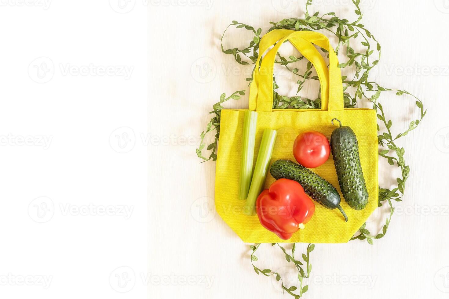 Cotton bag with seasonal vegetables for salad on white wooden background photo
