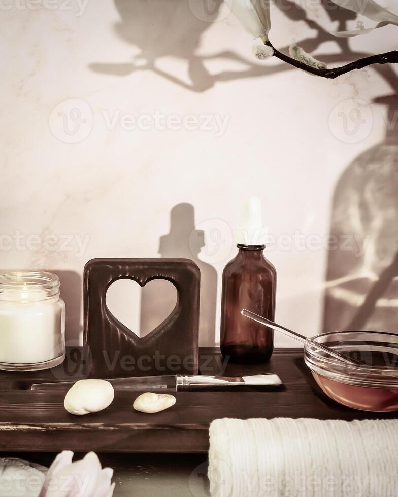 Cosmetology workplace with spa accessories, serum, candle and white towel on a wooden board photo