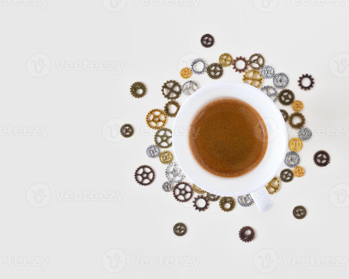 A cup of freshly brewed espresso around gears and cogs on a white background photo