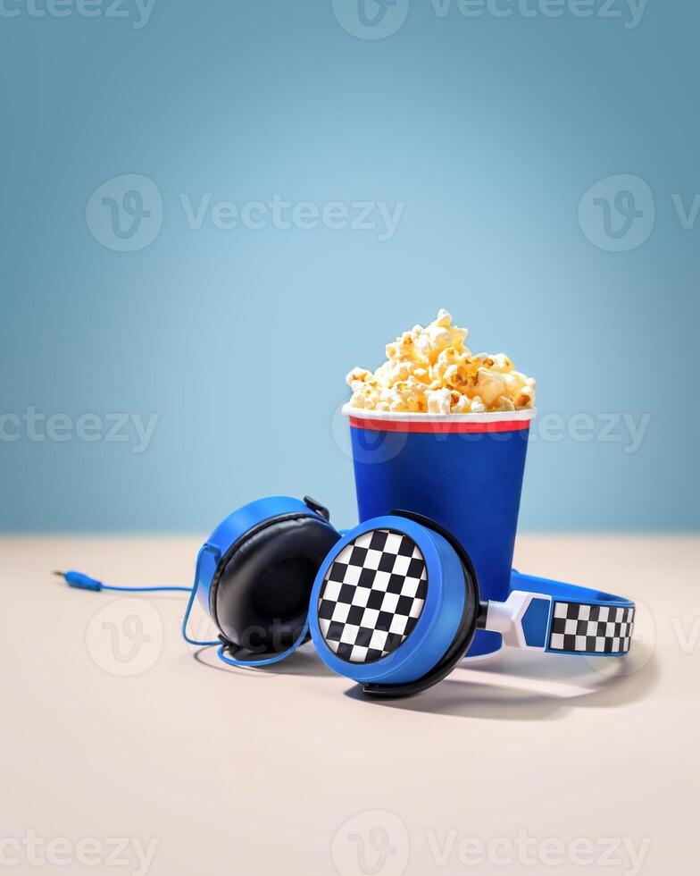 Disposable cup with popcorn and headphones on a light background. Movie concept photo