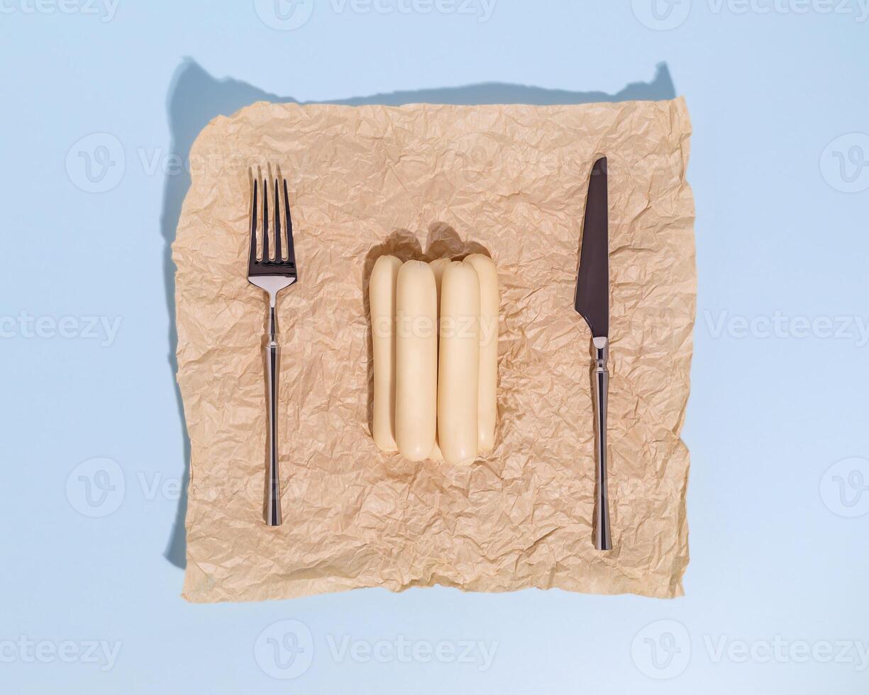 Raw poultry sausages on wrapping paper with a knife and fork photo