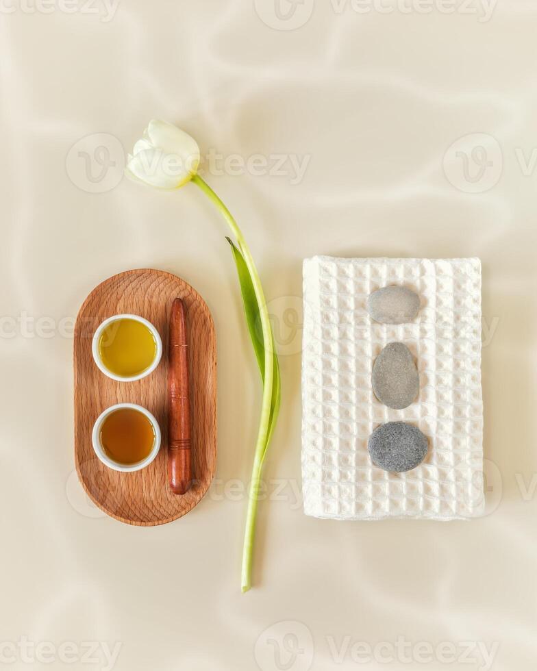Light, spa, wellness composition with towel, massage oil, massage stones and tulip photo