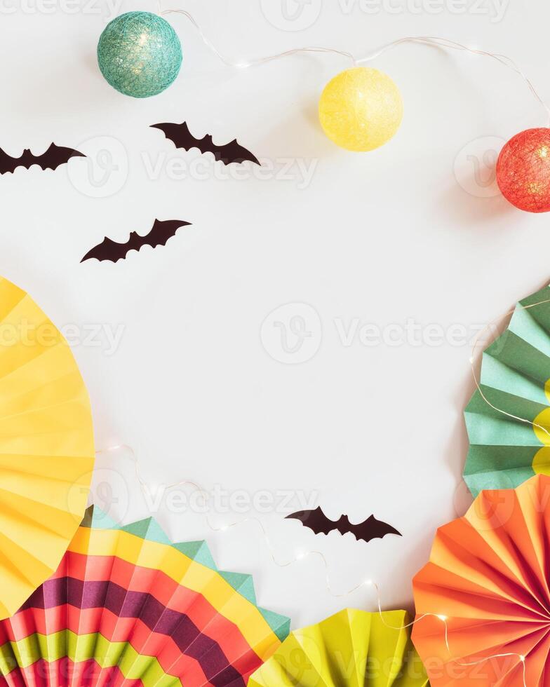 Helloween composition with colorful paper fans, helloween decorations and light garland on a blue background photo