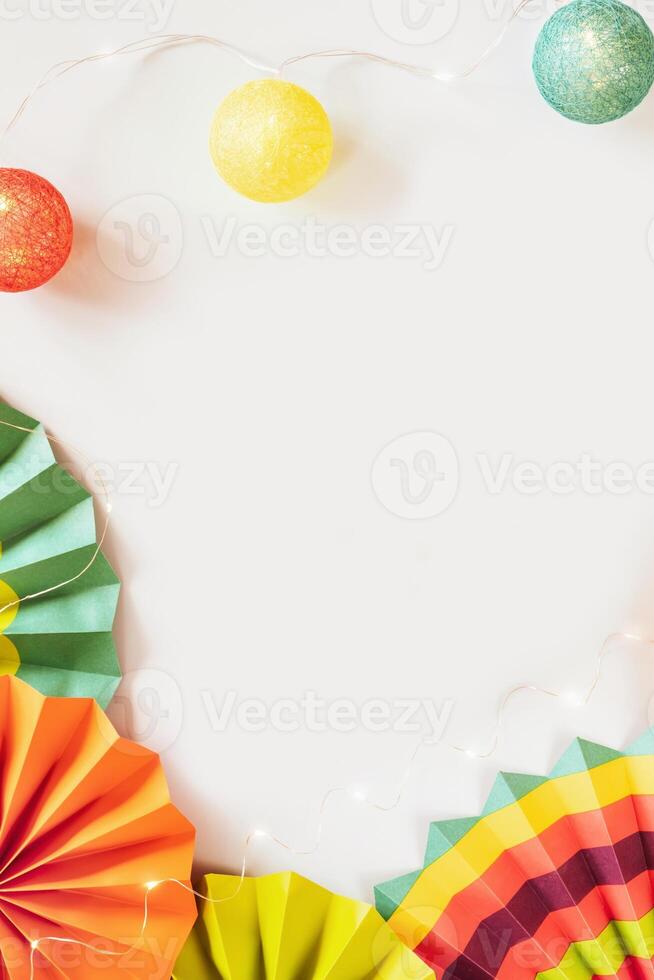 Carnival composition with colorful paper fans, light garland and copy space photo
