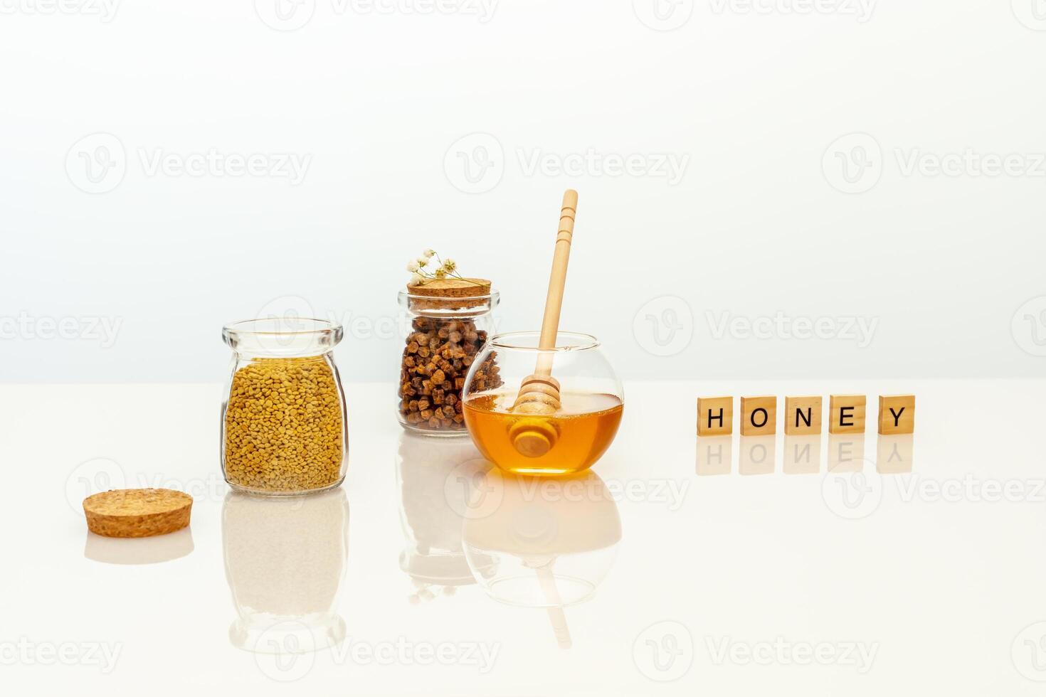 Natural bee products in glass jars and a wooden inscription honey on a white table photo