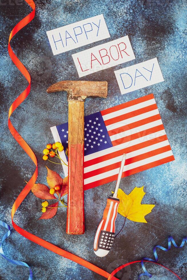 Inscription Happy labor day, american flag, hammer, screwdriver and autumn leaves on a blue background photo