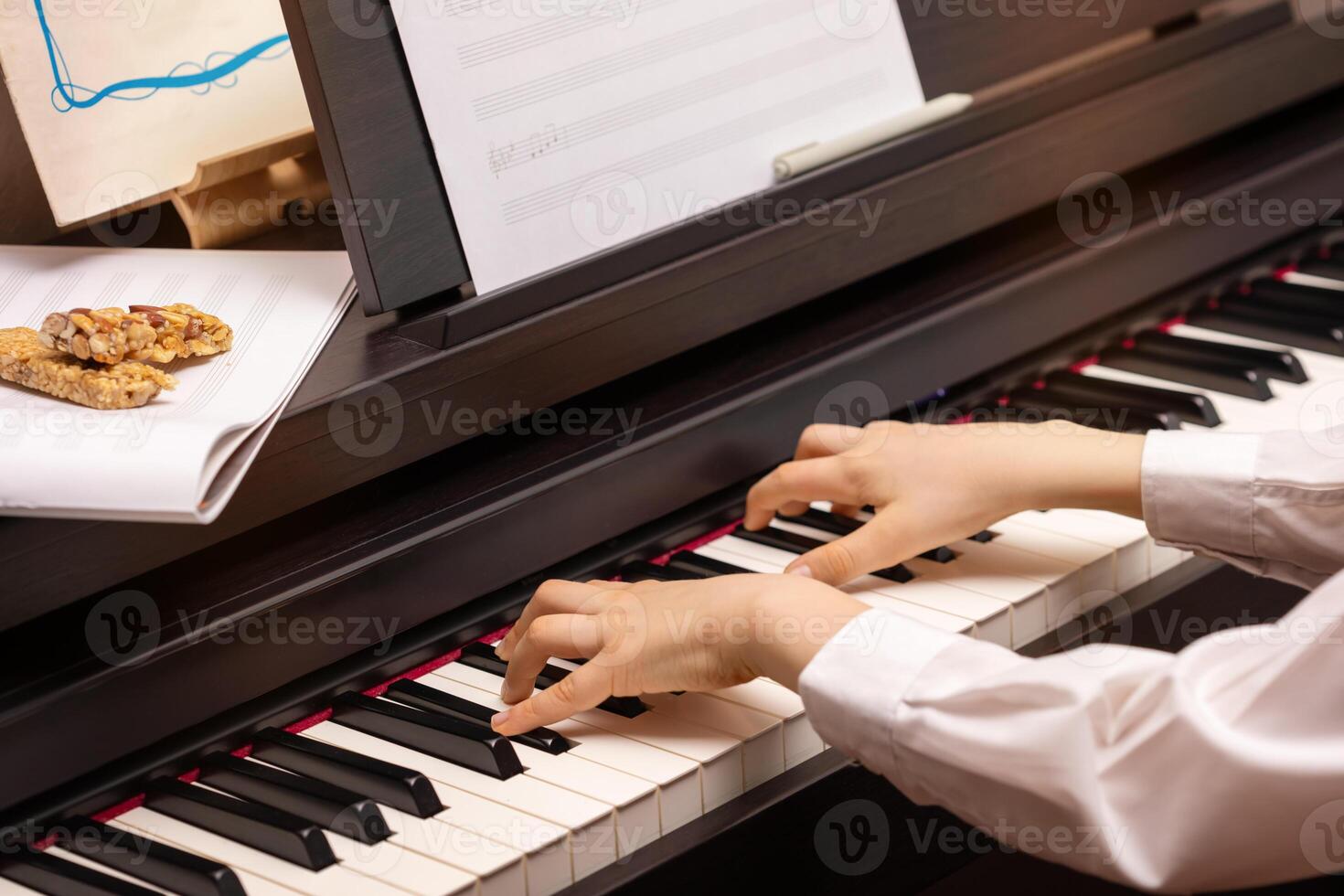 A boy plays the electronic piano with granola cereal bars photo