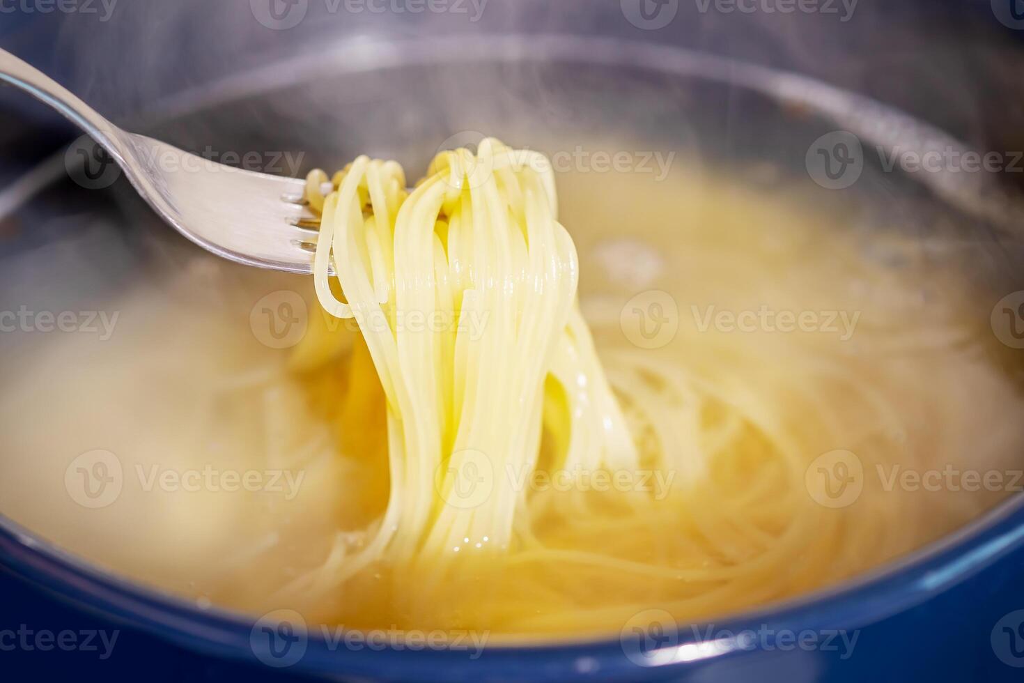 Spaghetti is cooked in boiling water in a saucepan photo
