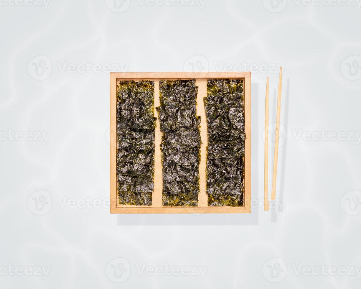 Organic dried seaweed snack on a wood board and chopsticks on a blue background photo