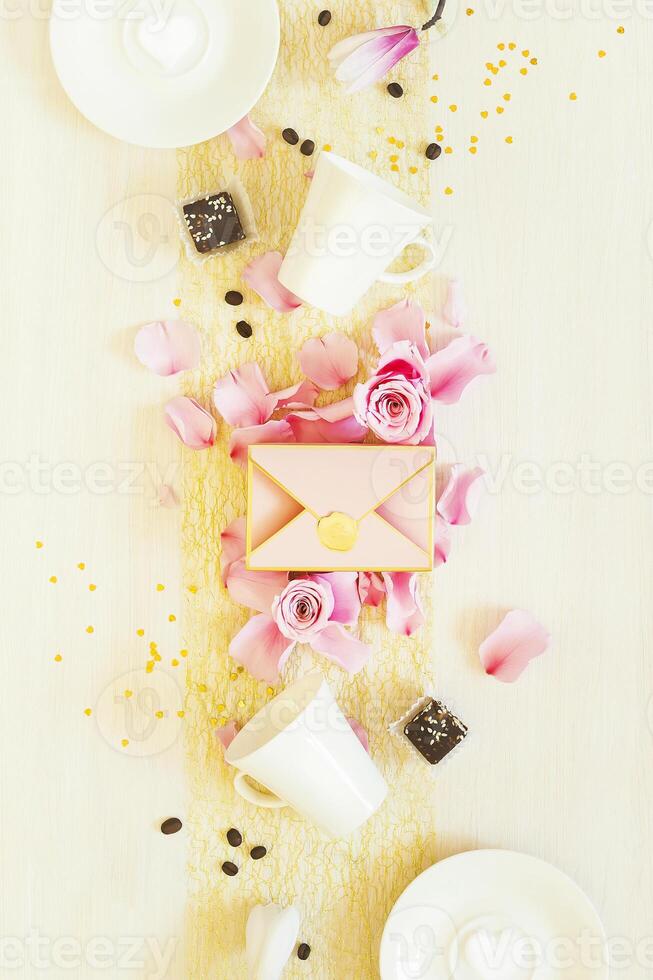 Still life with cups of coffee, sweets, a gift box and rose petals on white background photo