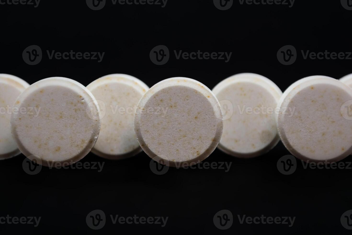 White pills on a black background. Focus on foreground, shallow depth of field. photo