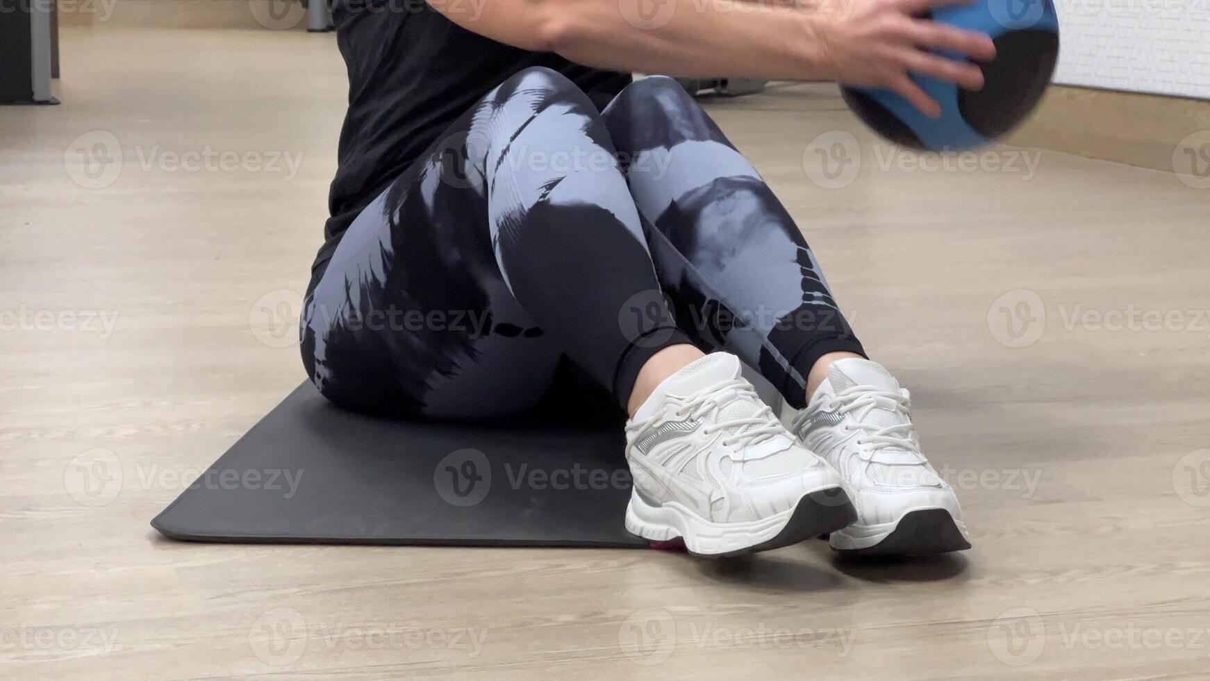 A woman in sportswear holds a ball and performs complex exercises for her abdominal muscles. photo