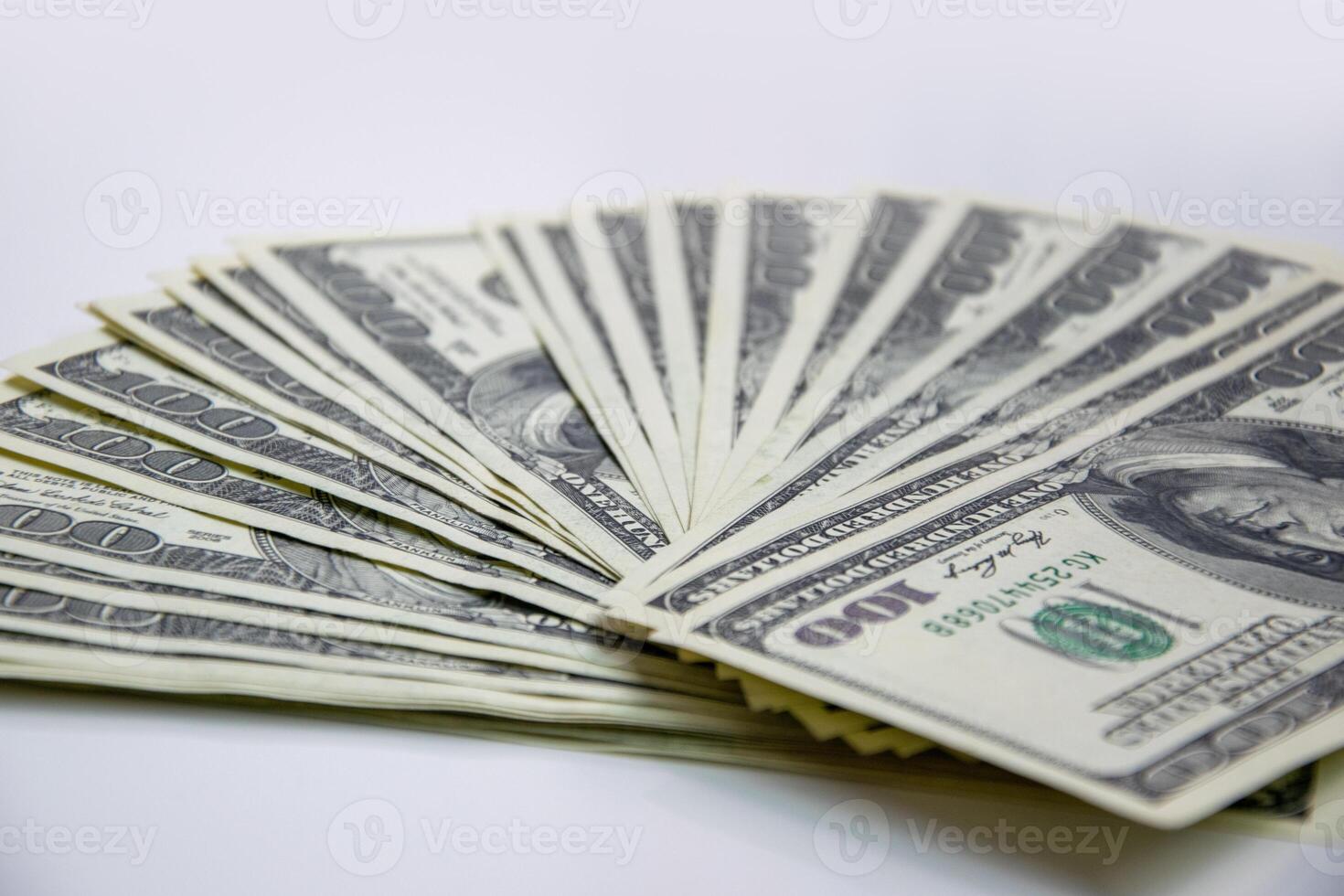 A closeup shot of a stack of new, hundred-dollar bills fanned out on a plain white background photo
