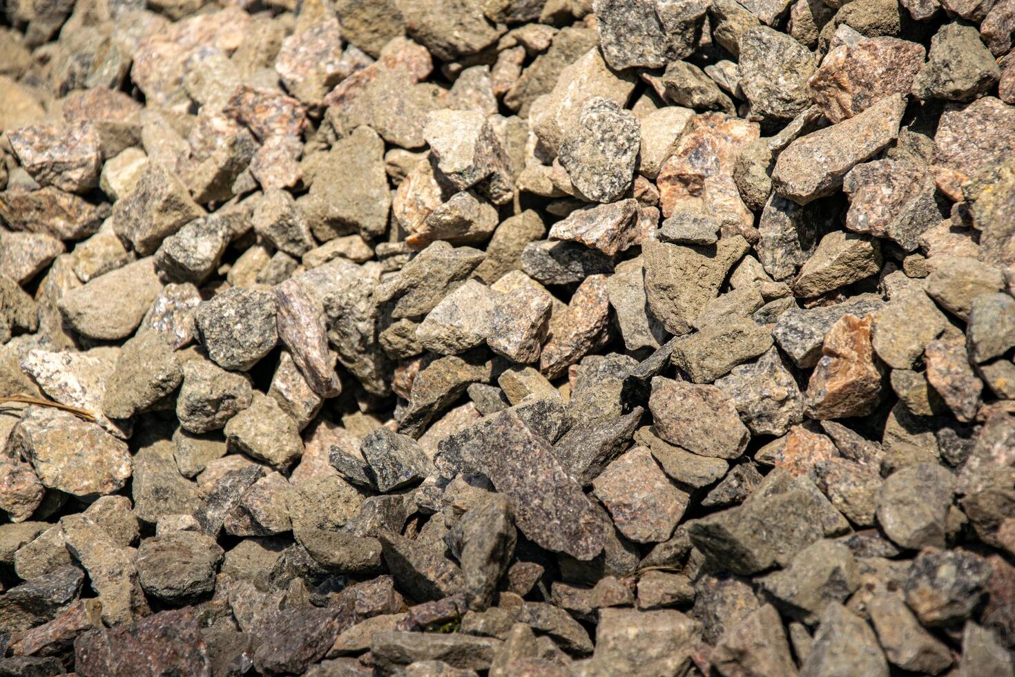 A close up image of a pile of crushed stone with varying shades of gray and brown. The stone is likely used for landscaping or construction purposes photo
