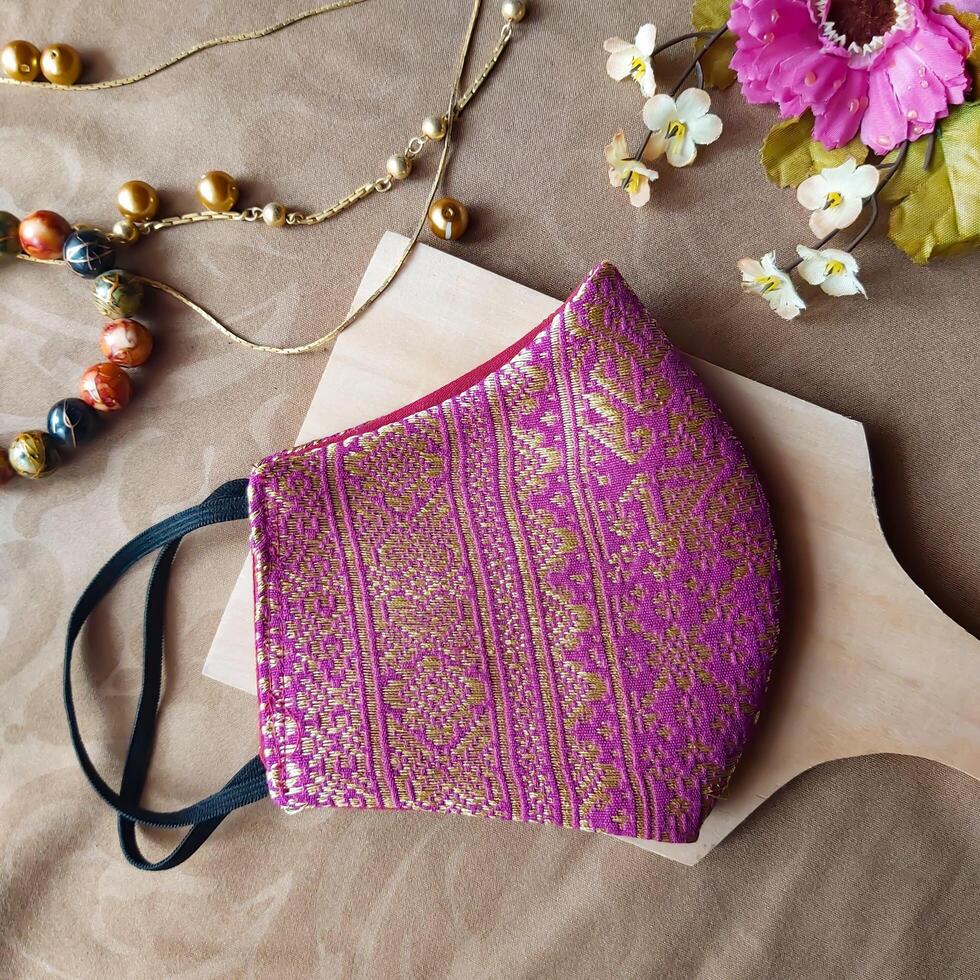 A handmade face mask made of traditional purple fabric with gold thread embellishments. photo