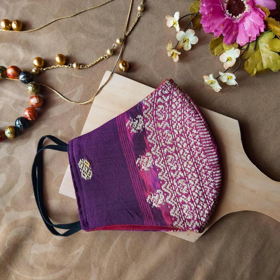 A handmade face mask made of traditional purple fabric with gold thread embellishments. photo