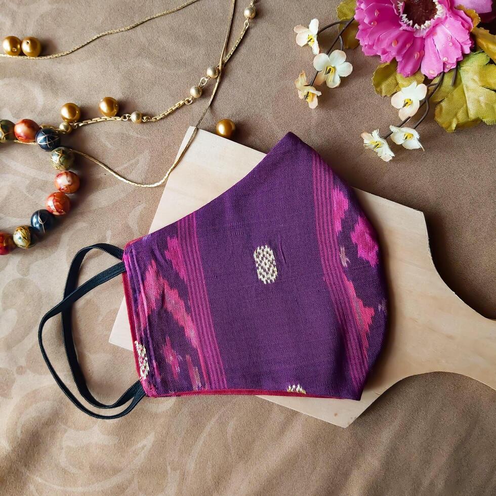 A handmade face mask made of traditional purple fabric with gold thread embellishments. photo