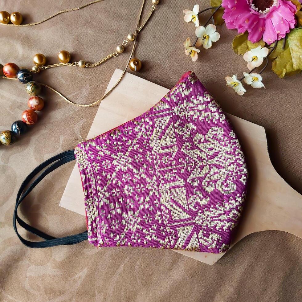 A handmade face mask made of traditional purple fabric with gold thread embellishments. photo