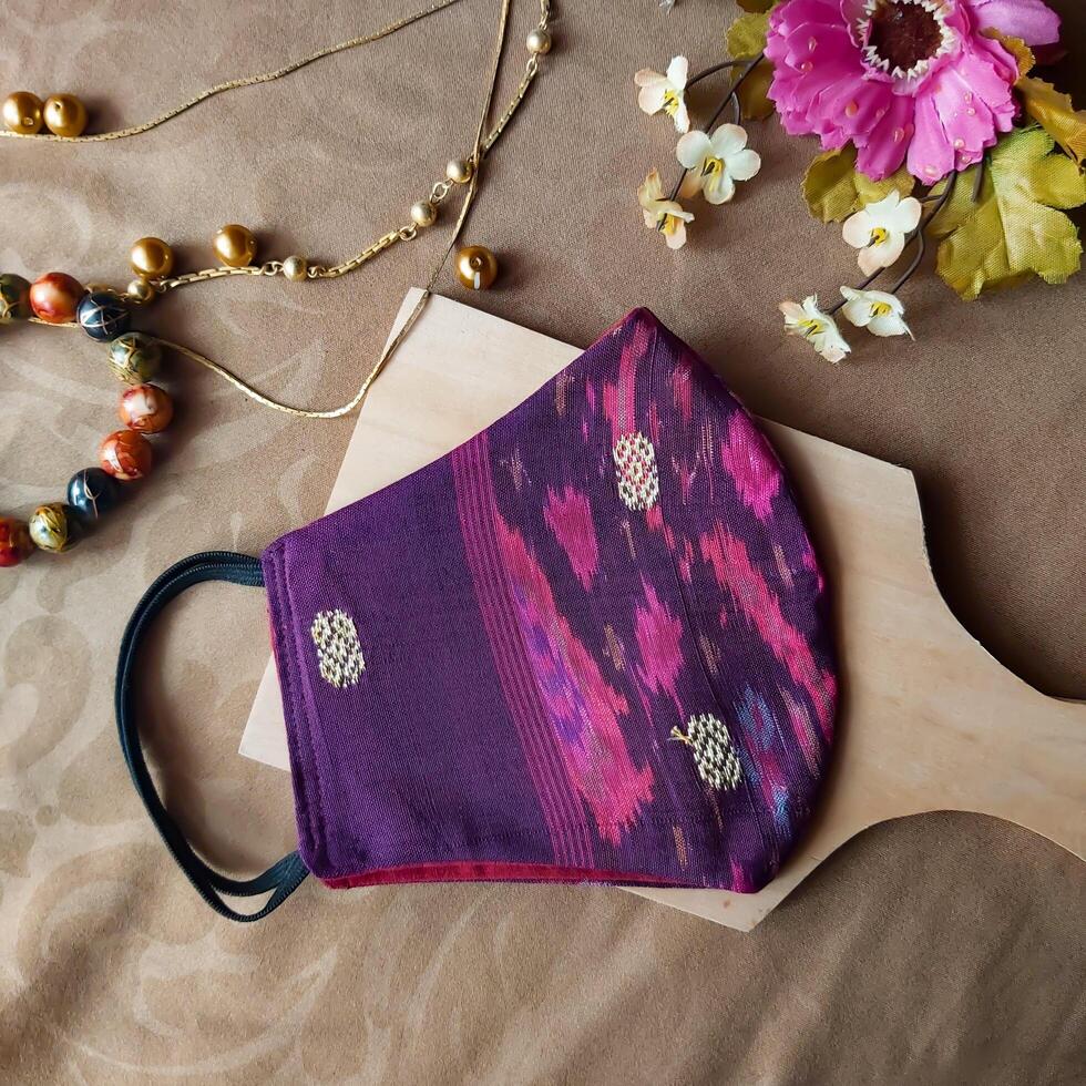 A handmade face mask made of traditional purple fabric with gold thread embellishments. photo