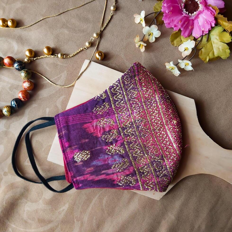 A handmade face mask made of traditional purple fabric with gold thread embellishments. photo
