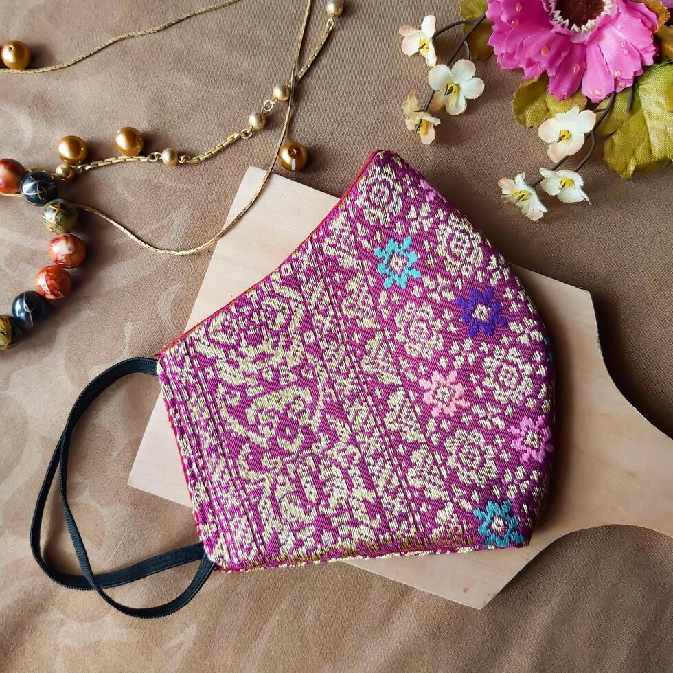 A handmade face mask made of traditional purple fabric with gold thread embellishments. photo