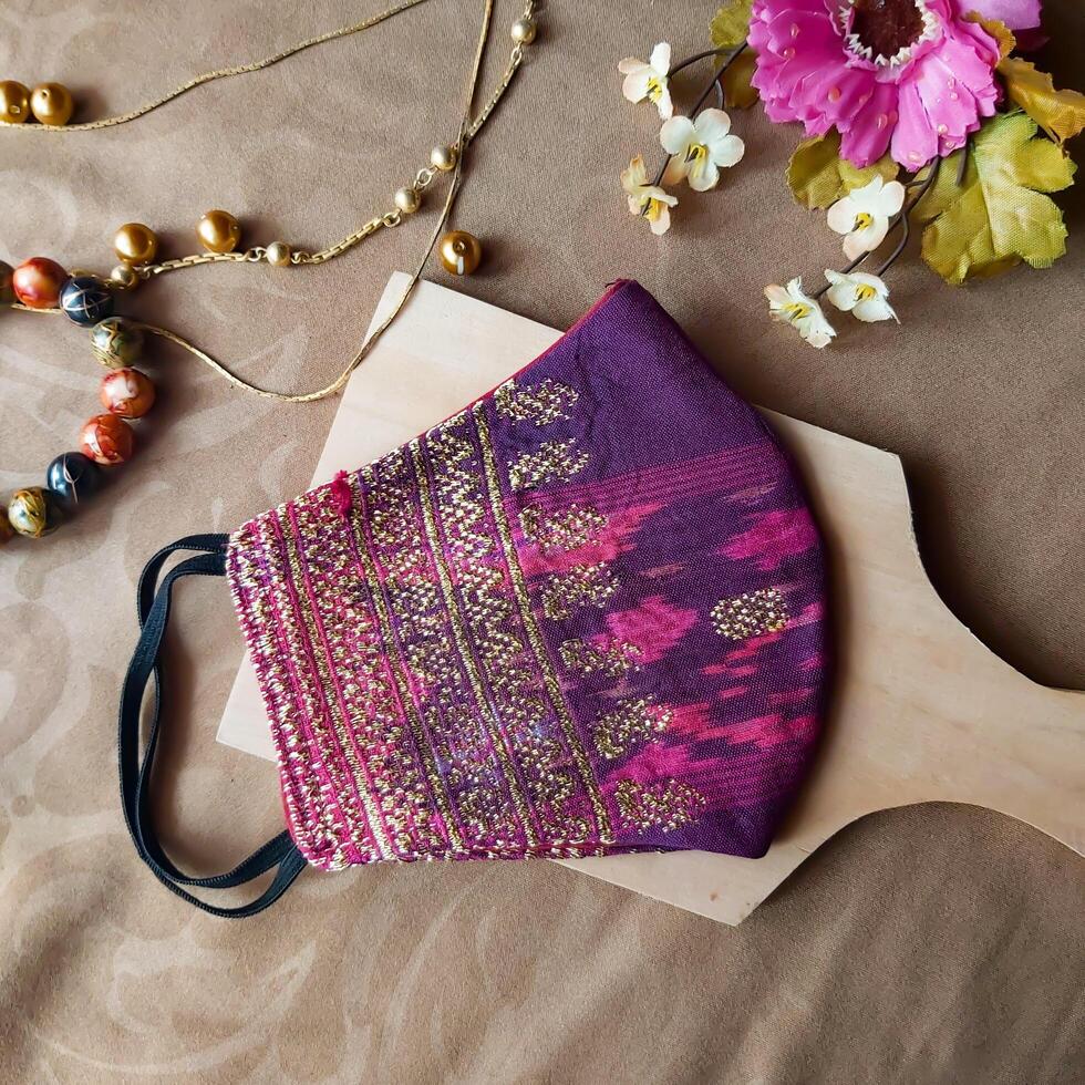 A handmade face mask made of traditional purple fabric with gold thread embellishments. photo