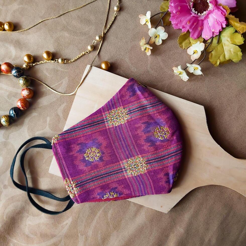 A handmade face mask made of traditional purple fabric with gold thread embellishments. photo