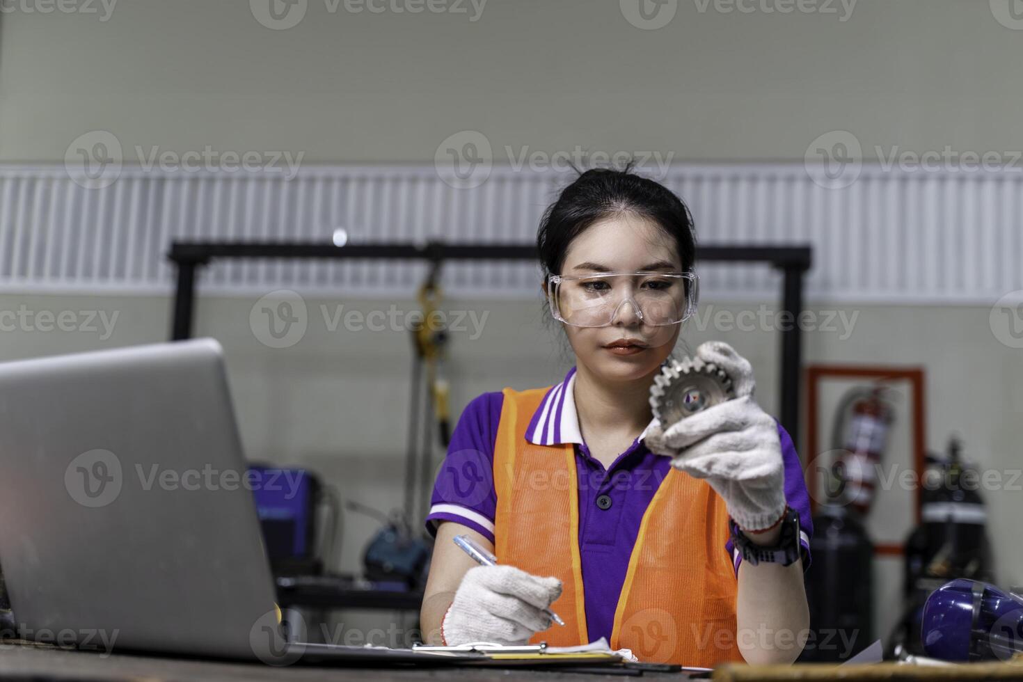 Closeup Asian woman technician engineer working designing mechanical parts engineering with laptop and example small gear in industrial workshop. photo