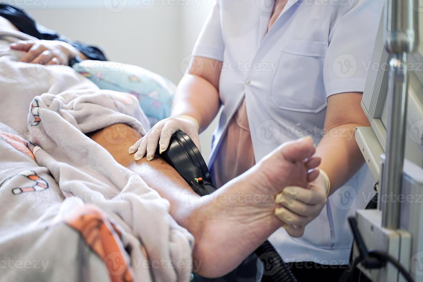 physical therapist using electrical muscle stimulation at elderly patient's legs in nursing homes photo