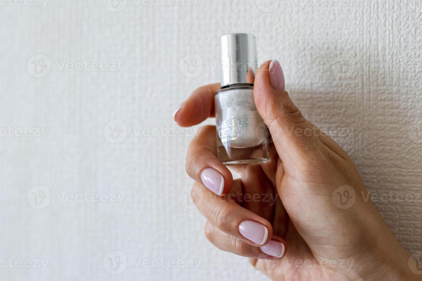 Shot of the beautiful woman's hand holding bottle of nail enamel. Beauty photo