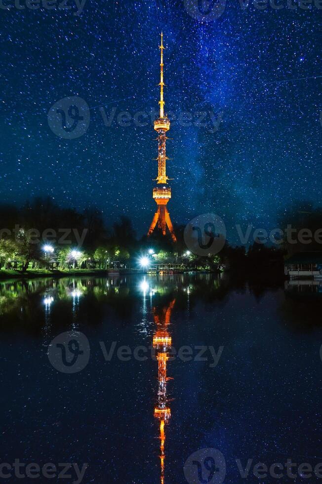 asian landmark illuminated TV tower at night in Tashkent in Uzbekistan with a reflection in water of river on background of a blue night sky with stars photo