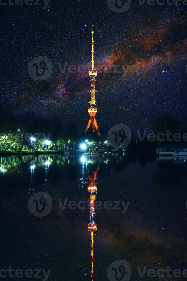 landmark television TV tower illuminated at night in Tashkent in Uzbekistan with a reflection in water of river on background of a starry sky with milky way photo