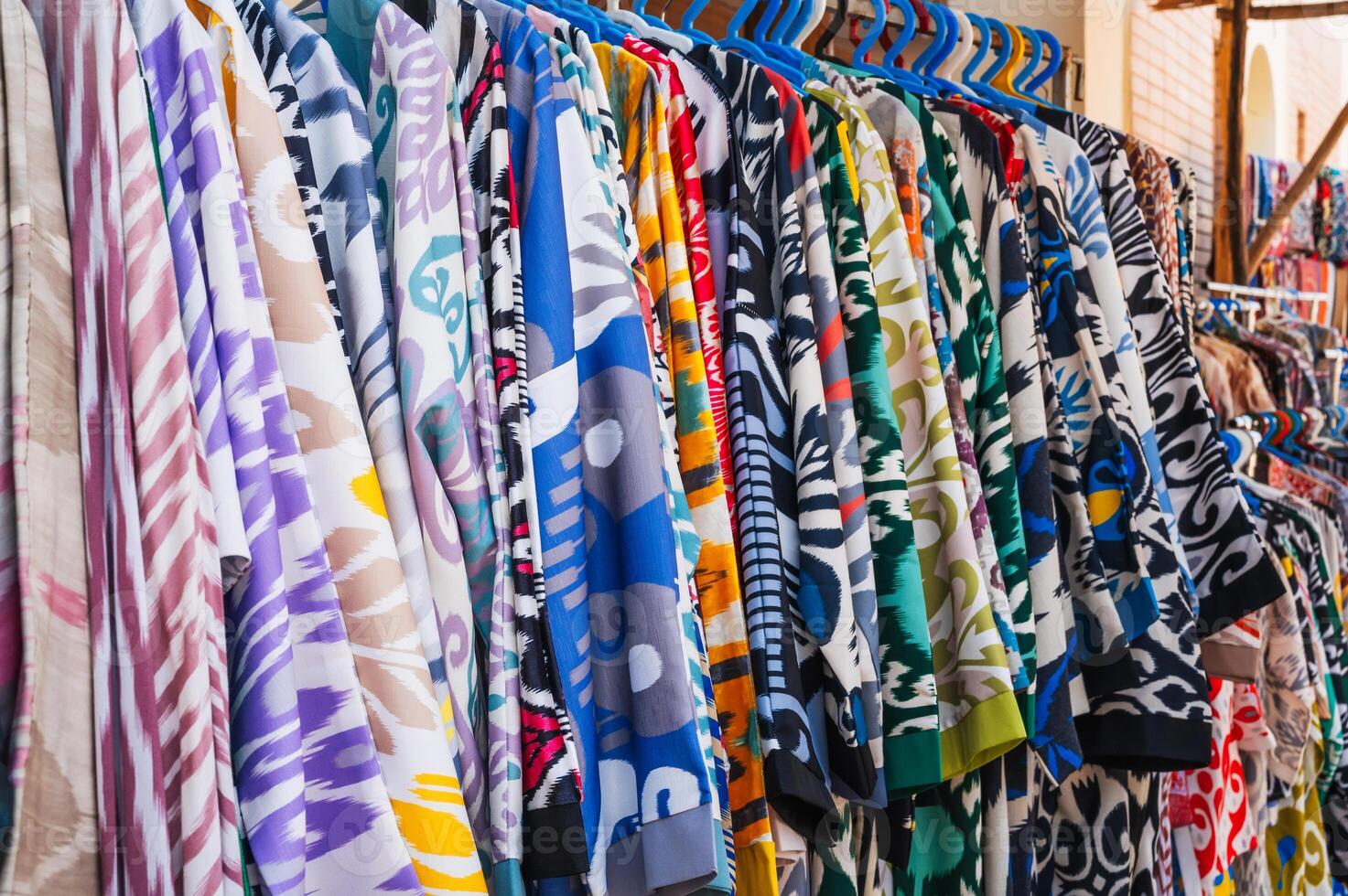 silk Asian Uzbek dresses with a bright colorful pattern in oriental street market of Uzbekistan close-up photo