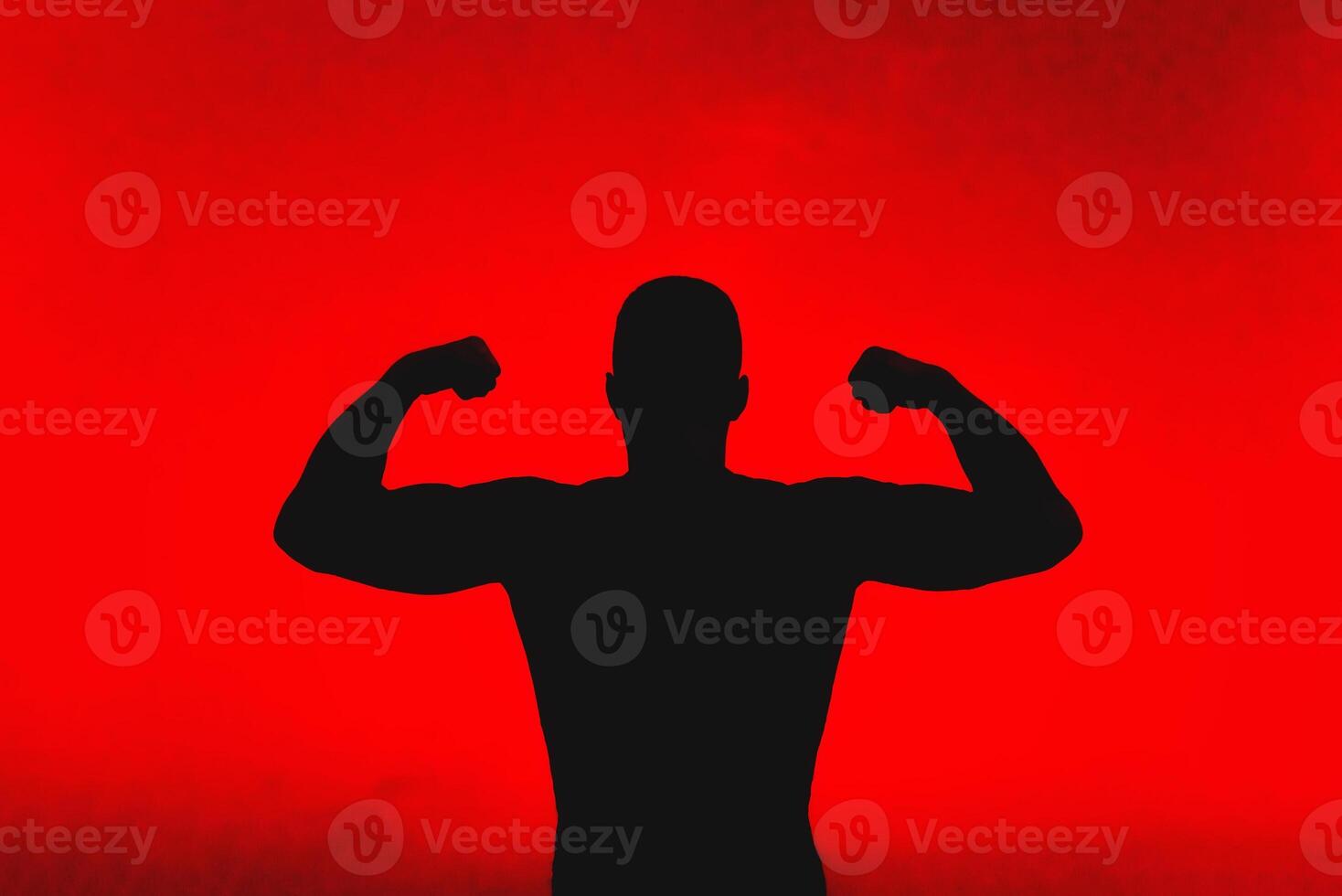 silhouette of a strong male showing off his muscles photo