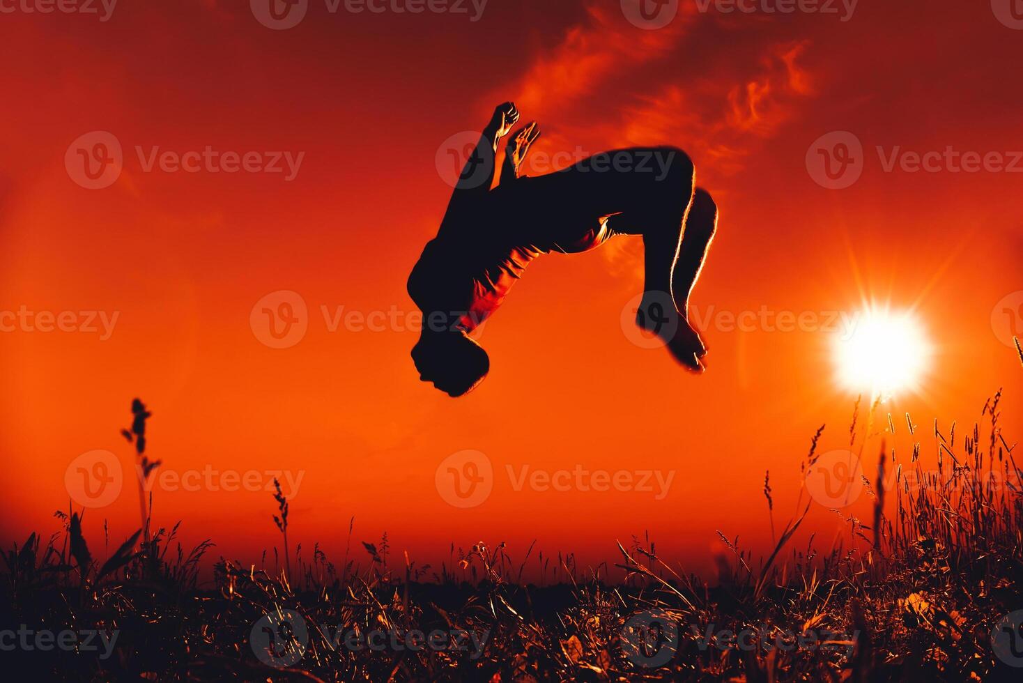 man jumps and does a back flip in the summer in nature photo