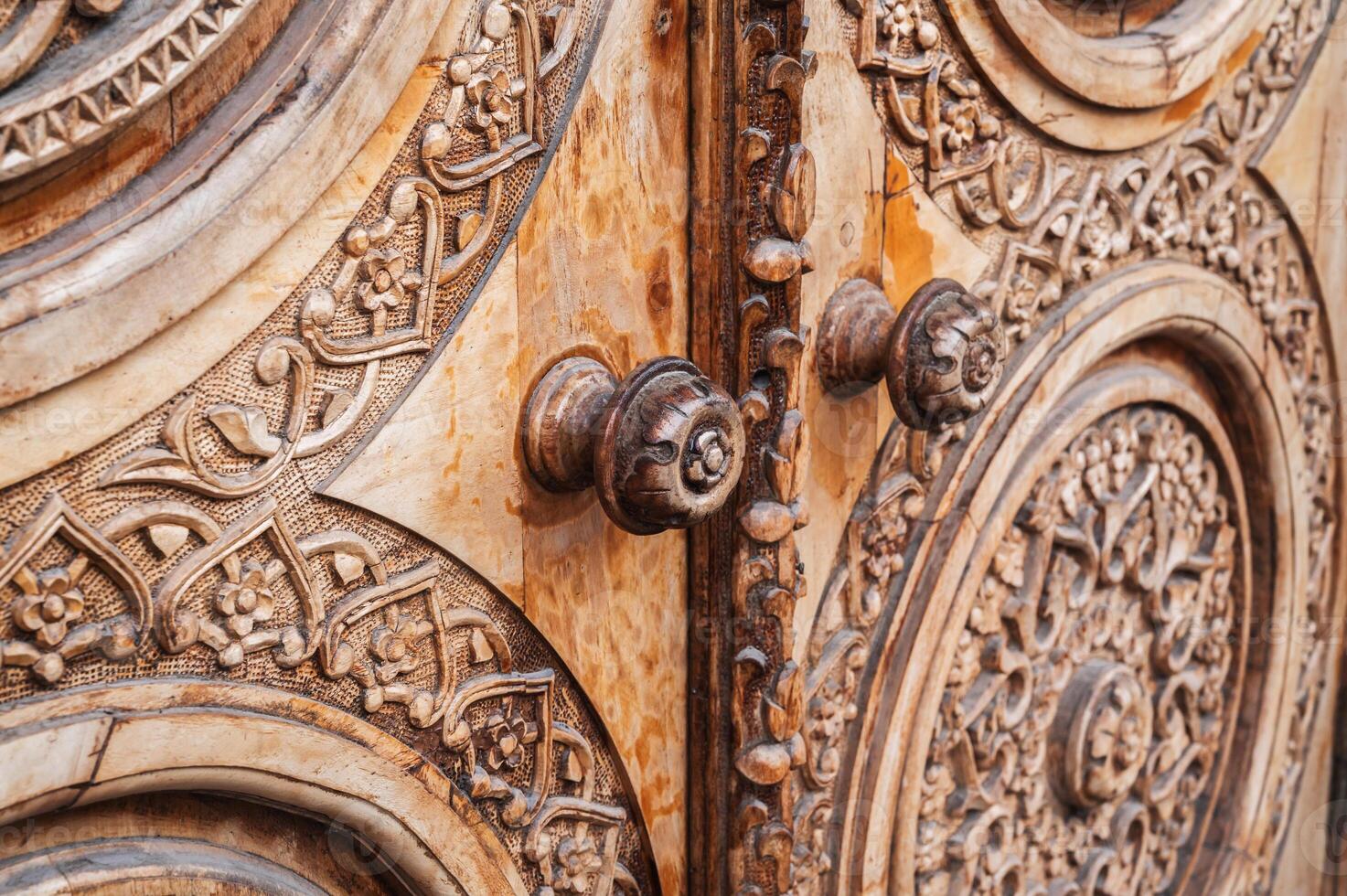 ancient carved wooden door with a traditional oriental Uzbek pattern ornament with old handles photo