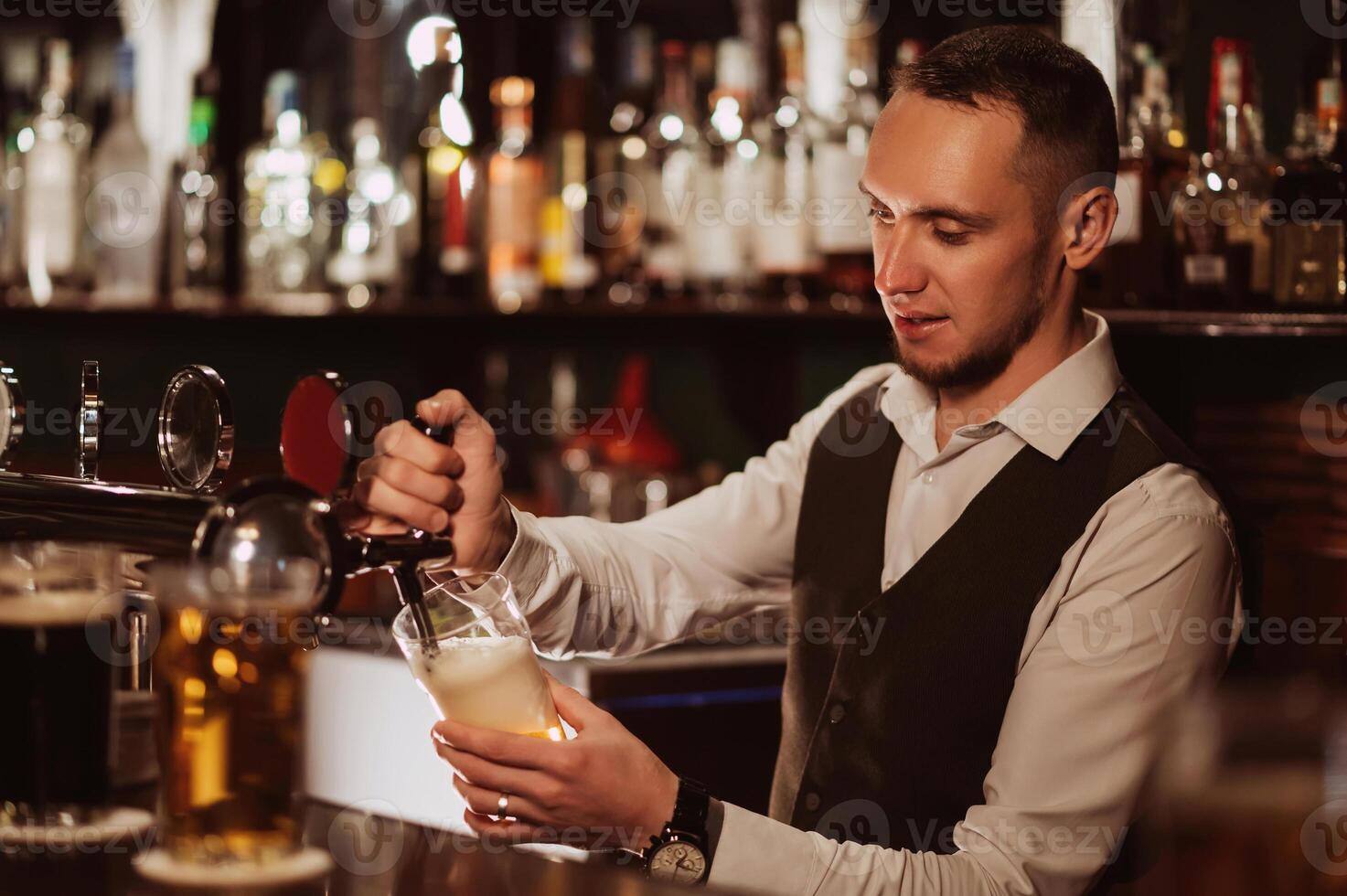 bartender pours draft beer into a glass from the tap behind the bar counter photo