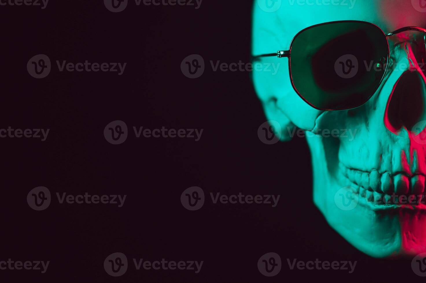 human skull wearing sunglasses with pink green neon light photo