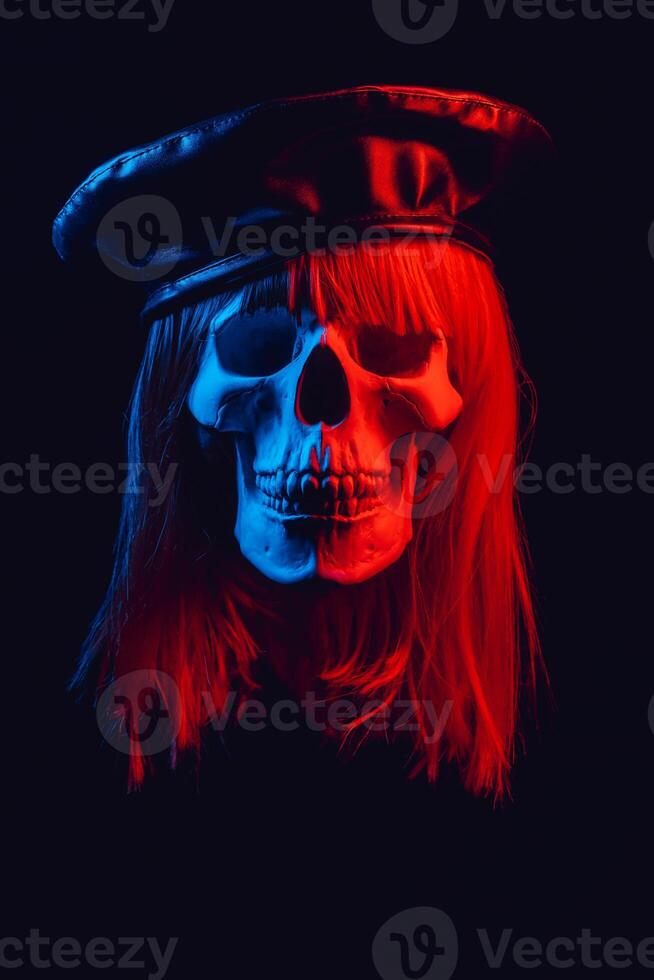 human skull of a woman in a wig with hair in a hat with colored red and blue light photo