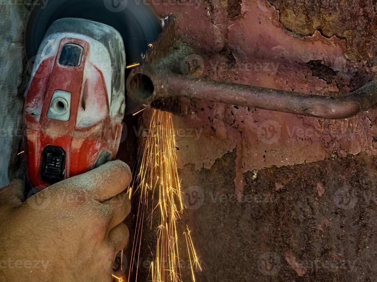 A worker cuts an old metal lock with a grinder. Sparks during operation photo