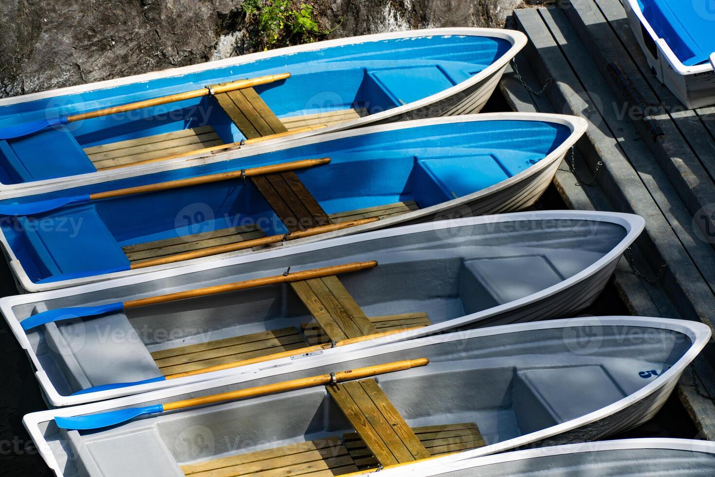 An overhead view of vibrant blue and white rowboats neatly docked at a wooden pier. Perfect for illustrating boating, summer activities, or waterfront scenes photo
