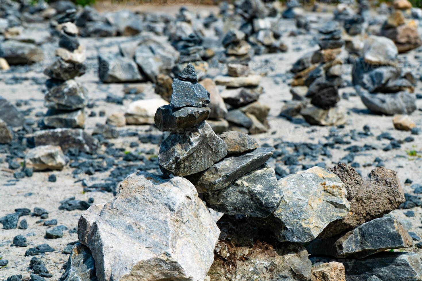 Close-up of a pile of stacked stones on a rocky terrain. The image captures the balance and arrangement of various rocks, showcasing the art of stone stacking in a natural outdoor setting. photo