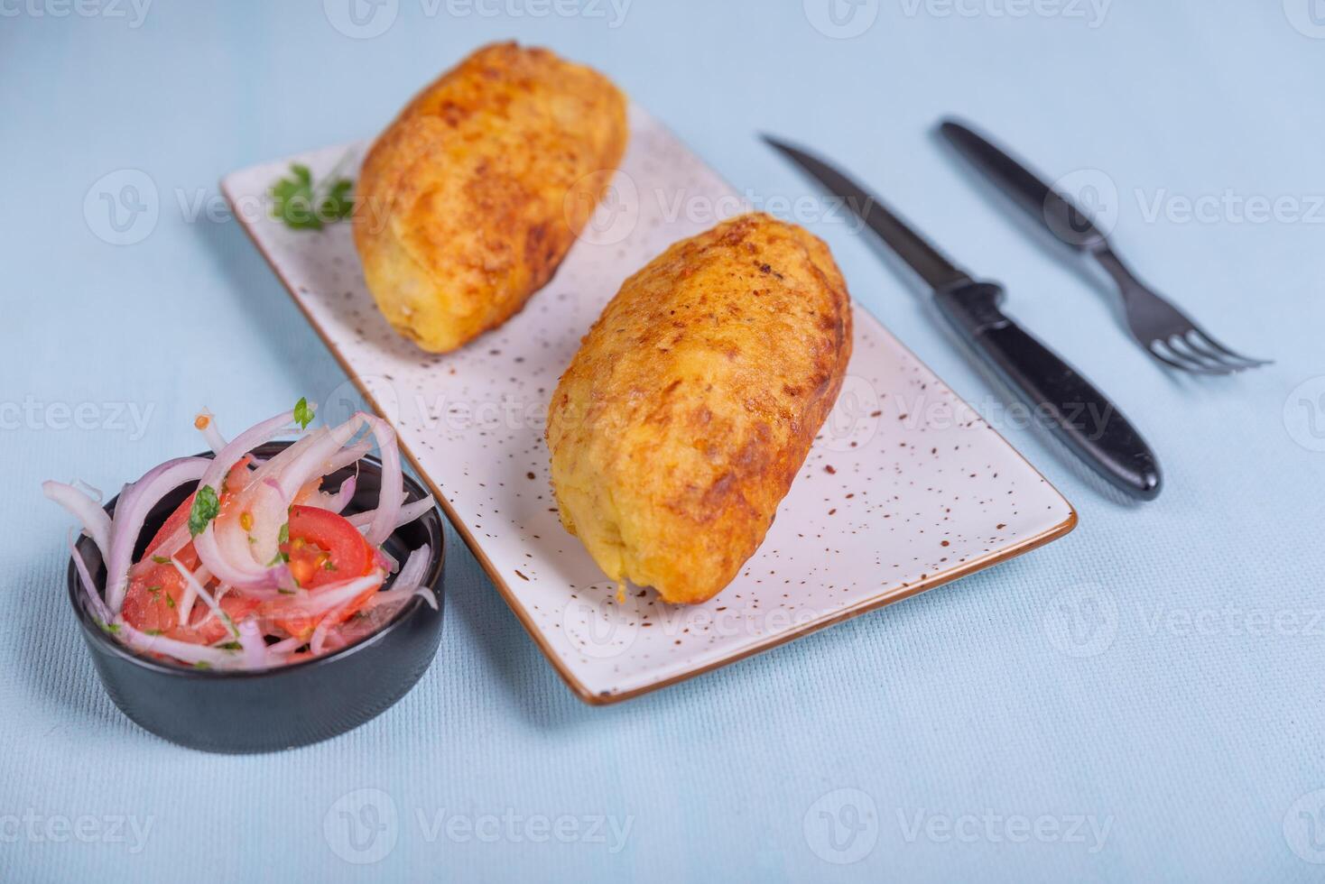 Creole dish called stuffed potato a crispy potato with a meat filling inside, accompanied by an onion and tomato salad. photo