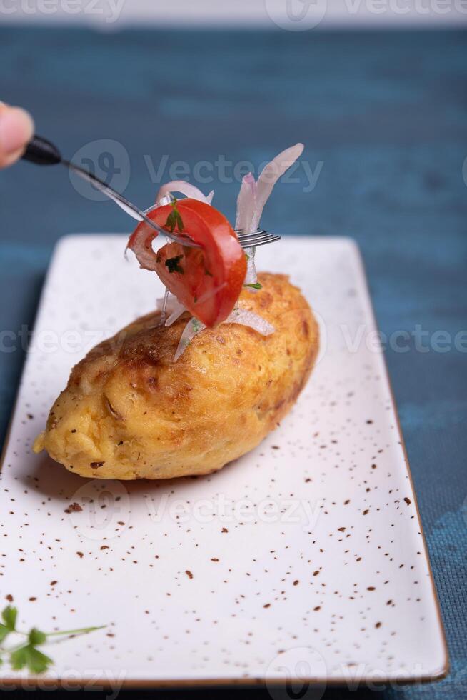 Hands with a fork putting salad on top of a stuffed potato. photo