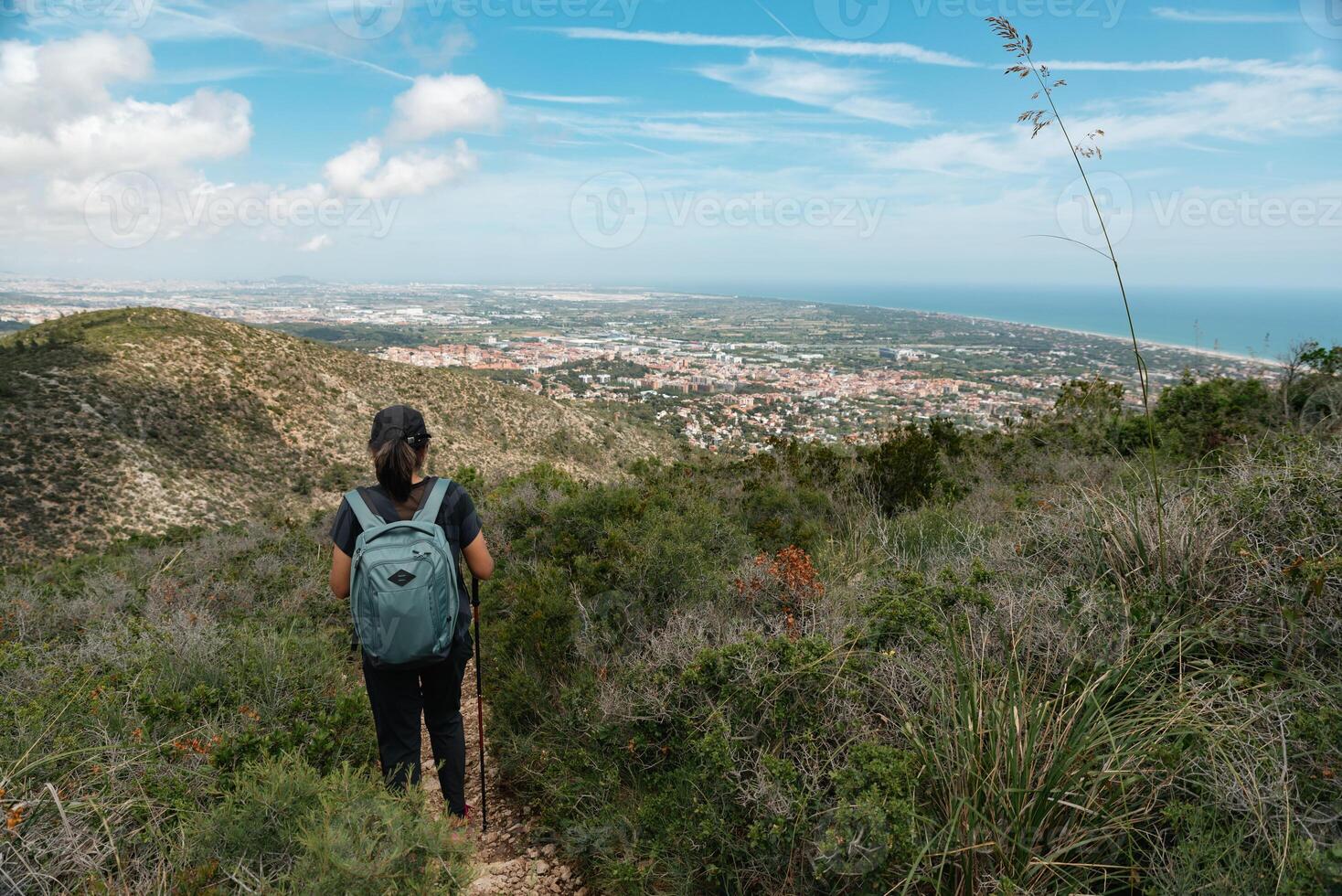 Hiker descending the mountain towards the city, with breathtaking views. photo