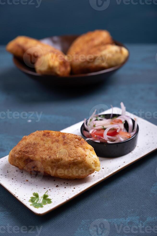 Close-up of crispy potatoes stuffed with savory delights and a salad on the side. photo