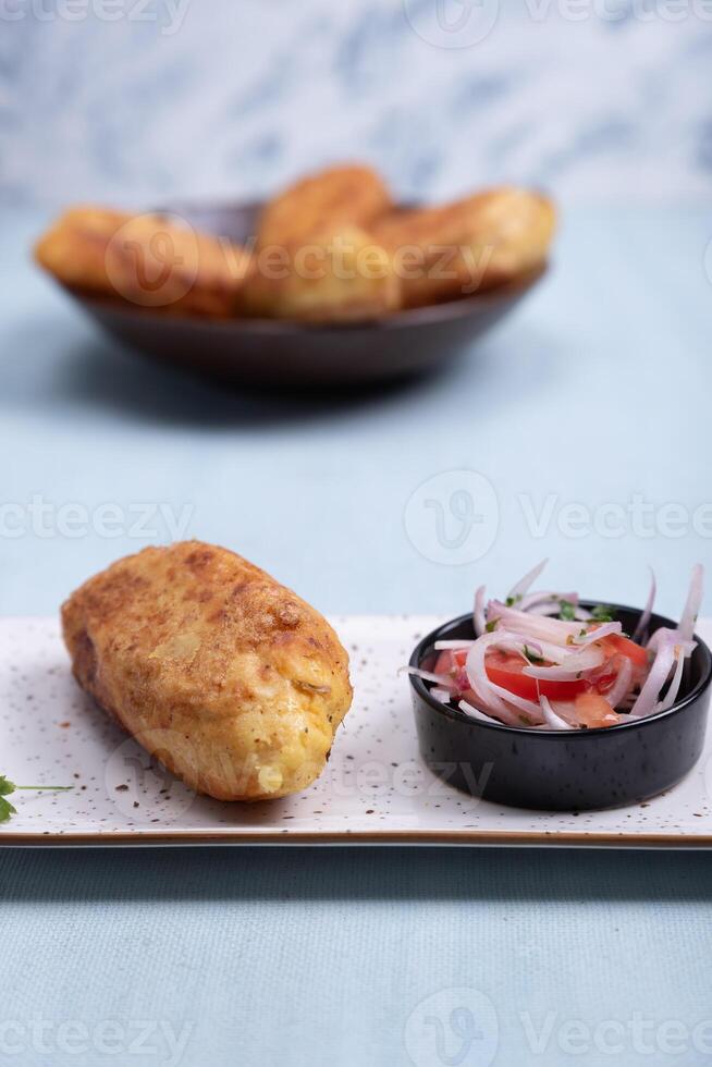 Close-up of golden potato stuffed with tasty stuffing, accompanied by an onion and tomato salad. photo