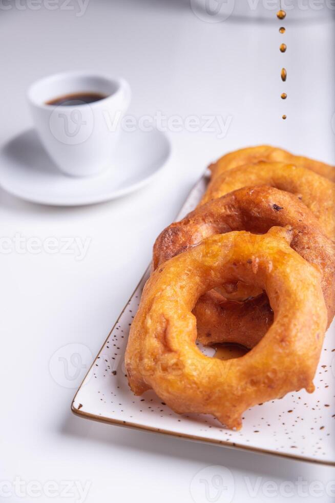 Drops of honey falling on the traditional Peruvian dessert called Picarones. photo